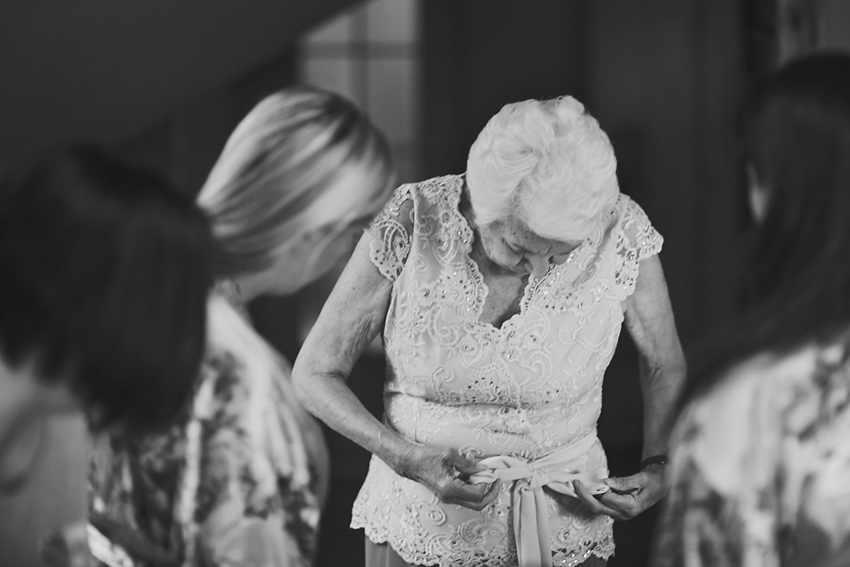 babcia-przygotowania-do-slubu 12 Starsza kobieta poprawia wstążkę w sukni przygotowując się do ślub